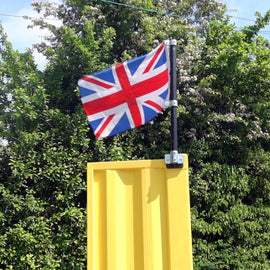 Union Jack flag attached to a yellow shipping container using the sign kit with trees in the background