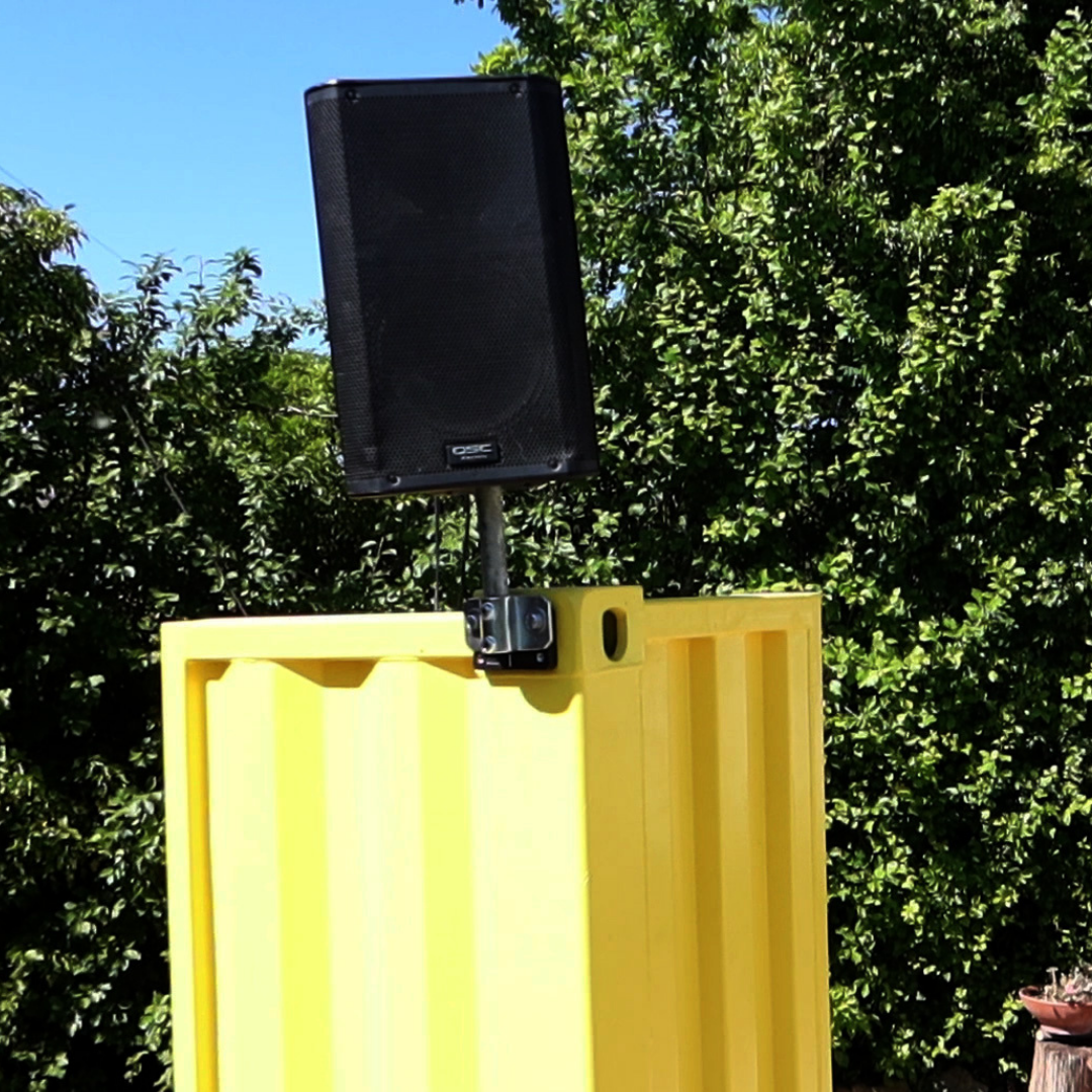 A speaker attached to a shipping container using a Domino Clamp
